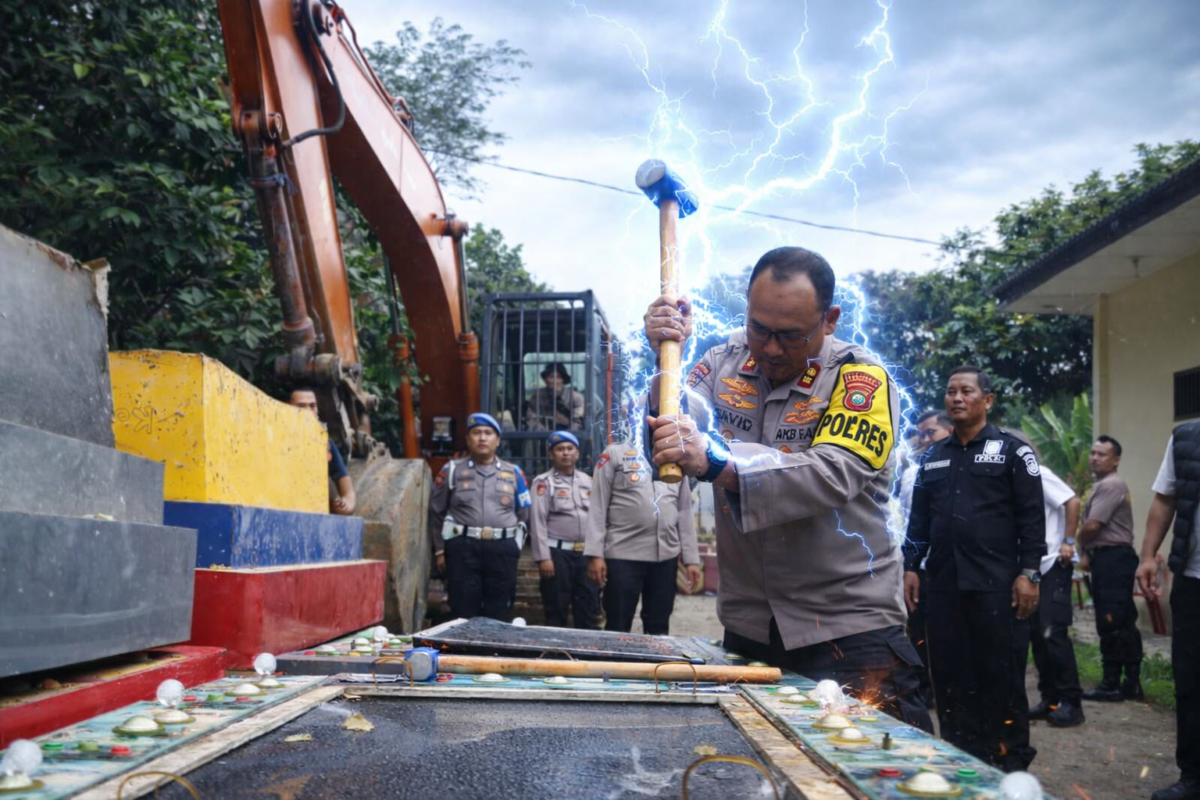 Kapolres Langkat menghancurkan mesin judi menggunakan martil besar (Foto: edit tim Langkatoday)